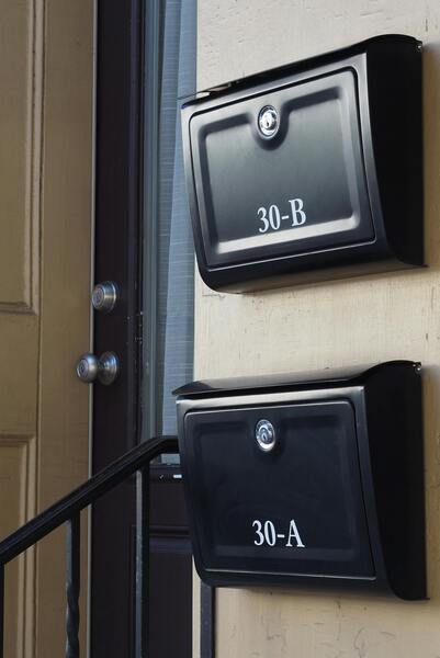 black mailboxes on tan wall by door